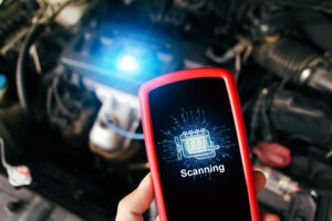 Car engine scanning with wireless technical tool, OBD2 scanner tool in a mechanic hand with a car engine compartment blurred on background, Car maintenance service concept